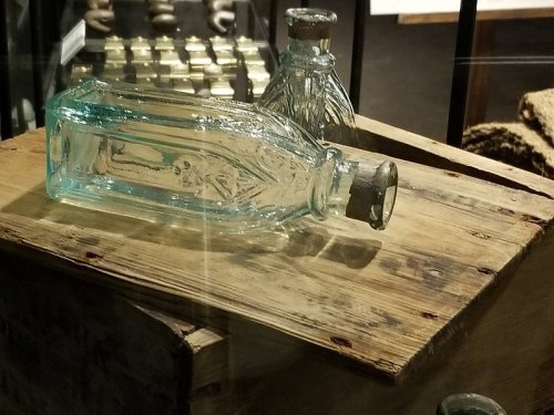 Two vintage glass bottles on a wooden surface, with one bottle tipped over.