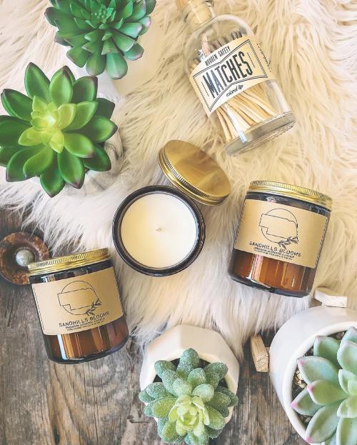 A flat lay of candles, a bottle of matches, and succulents on a textured surface.