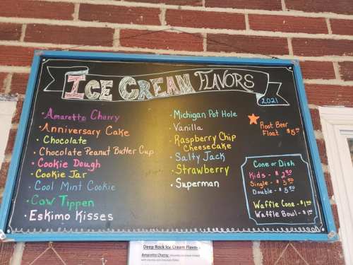 Chalkboard menu listing various ice cream flavors and prices, including Amaretto Cherry, Vanilla, and Superman.