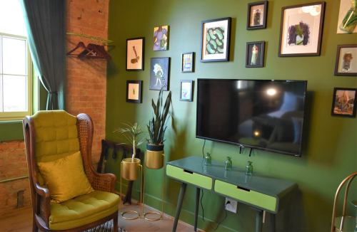 Cozy room with green walls, a vintage chair, a TV, and a gallery of framed art on the wall.