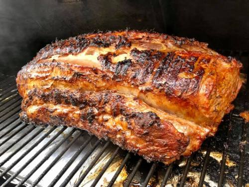 A large, perfectly cooked piece of meat with a crispy, charred exterior resting on a grill.