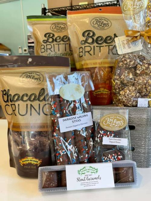 A variety of sweet treats including chocolate crunch, brittle, walking sticks, and caramels displayed on a table.