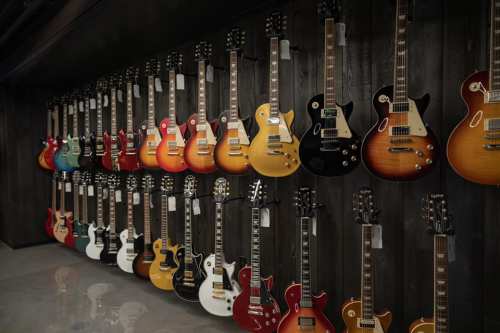 A wall display of various electric guitars in different colors and styles, neatly arranged in a music store.