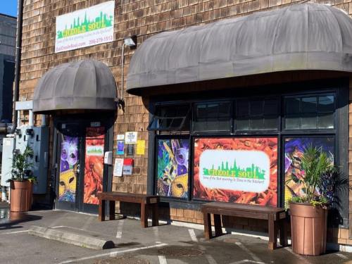 Exterior of a restaurant called "Creole Soul," featuring colorful banners and outdoor seating.