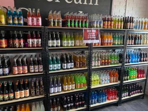 A colorful display of various soda bottles arranged on shelves in a store.