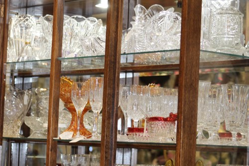 A display cabinet filled with various crystal glassware, including vases, bowls, and elegant drinking glasses.