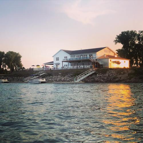 A waterfront restaurant at sunset, with boats nearby and a warm glow reflecting on the water.