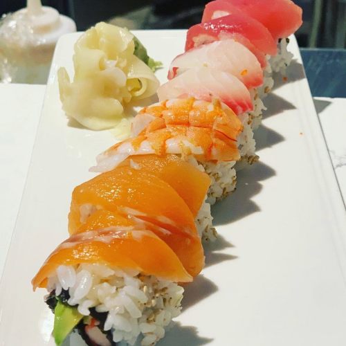 A plate of sushi featuring various colorful fish slices on rice, accompanied by pickled ginger.