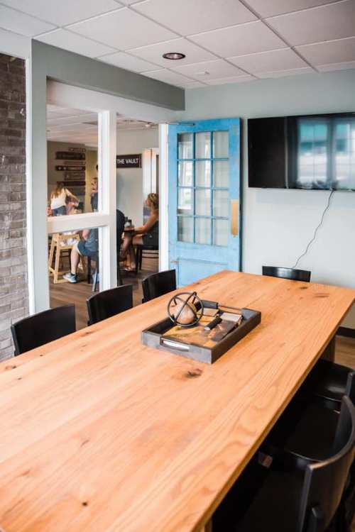 A spacious dining area with a wooden table, black chairs, and a blue door leading to another room.