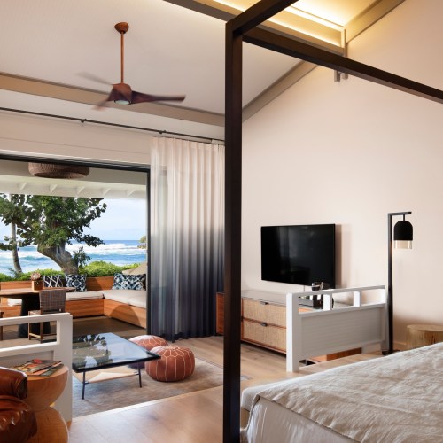 Modern coastal living room with large windows, a view of the ocean, and stylish furniture.
