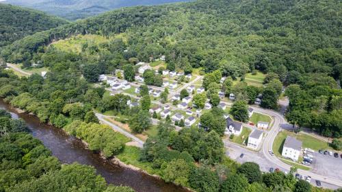 Aerial view of a small town surrounded by lush greenery and a river, featuring residential homes and winding roads.