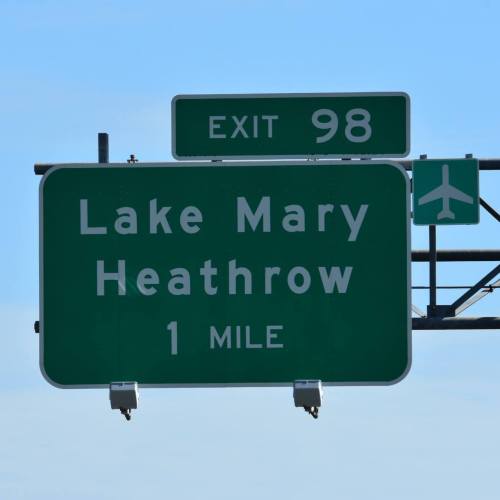 Green highway sign indicating "Exit 98" for Lake Mary and Heathrow, 1 mile ahead.