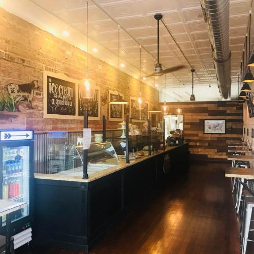 Cozy ice cream shop interior with wooden accents, display counter, and warm lighting.