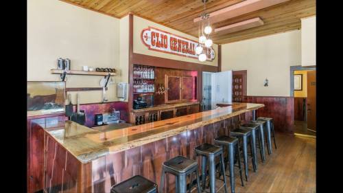 A rustic bar with a wooden countertop and black stools, featuring vintage decor and a warm, inviting atmosphere.