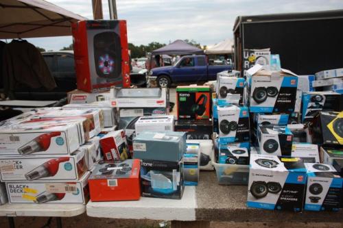 A variety of electronic products and accessories displayed on a table at an outdoor market.