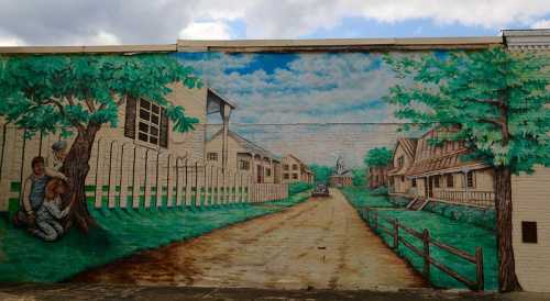 A colorful mural depicting a serene street scene with houses, trees, and people sitting under a tree.