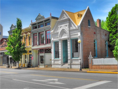 Historic buildings line a street, showcasing colorful facades and architectural details under a clear blue sky.