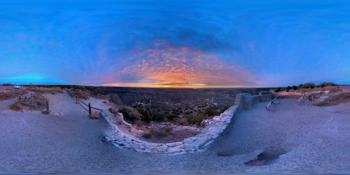A panoramic view of a canyon at sunset, with vibrant clouds and a serene landscape.