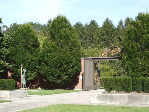 A decorative gate surrounded by lush greenery and trees in a serene outdoor setting.