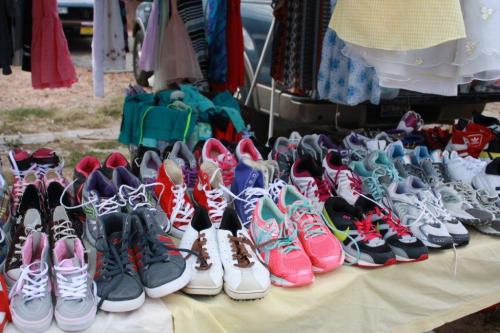 A variety of colorful sneakers and athletic shoes displayed on a table at a market.
