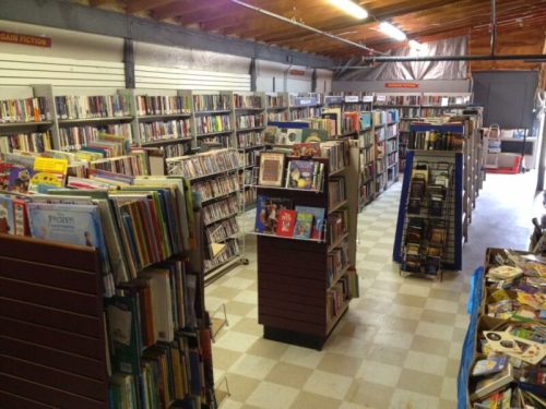 A spacious library interior with rows of bookshelves filled with various books and a few display stands.