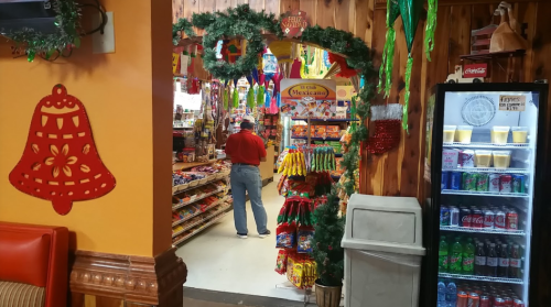 A person browsing snacks in a colorful store decorated for the holidays, with shelves filled with various products.