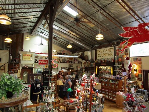 A vintage shop interior filled with antiques, candy displays, and nostalgic decor under a metal roof.
