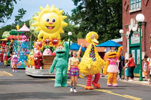 A colorful parade featuring cheerful characters, including Big Bird and other beloved puppets, along a festive street.