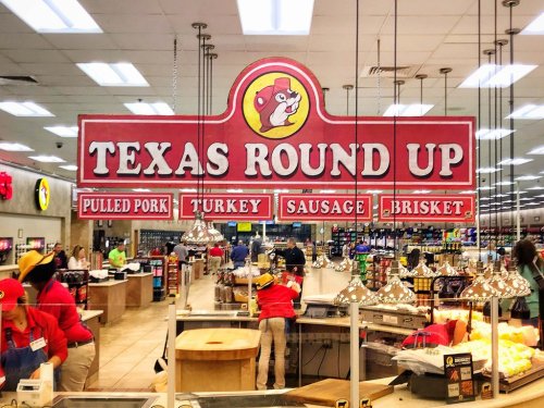 Sign for "Texas Round Up" featuring pulled pork, turkey, sausage, and brisket in a bustling food market.