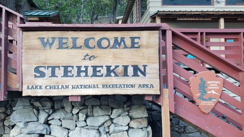 Welcome sign for Stehekin at Lake Chelan National Recreation Area, featuring wooden lettering and stone base.