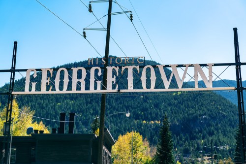 Sign reading "Historic Georgetown" against a backdrop of mountains and clear blue sky.
