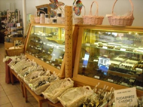 Display of assorted candies and chocolates in a shop, featuring glass cases and baskets filled with treats.