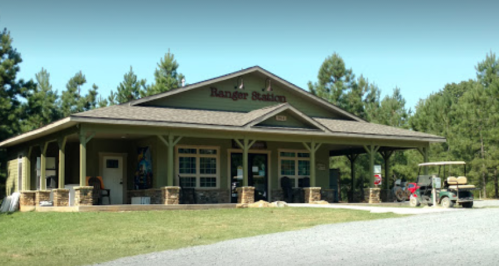 A green ranger station with a stone foundation, surrounded by trees and a golf cart parked outside.