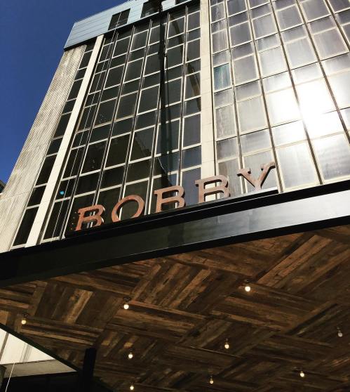 Exterior view of a building with large windows and a sign that reads "BOBBY" in bold letters.