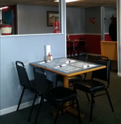 A small, casual dining area with a wooden table and black chairs, featuring red and blue walls and simple decor.