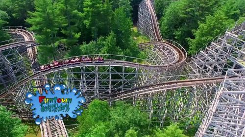 Aerial view of a wooden roller coaster winding through lush green trees, with a playful splash-themed logo at the bottom.