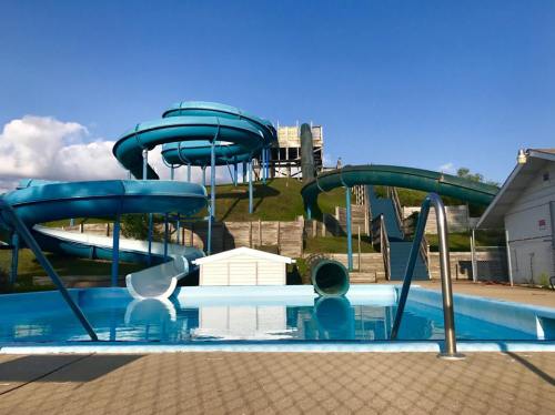 A swimming pool with blue water slides in the background under a clear blue sky.