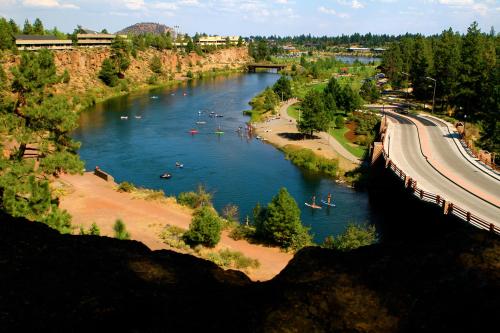 A scenic view of a river surrounded by trees, with people kayaking and a bridge in the background.