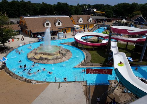 Aerial view of a water park featuring slides, a fountain, and people enjoying the pool area.