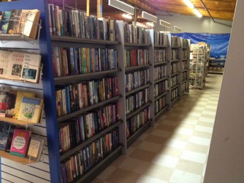 A view of a library aisle lined with bookshelves filled with various books, with a cozy, inviting atmosphere.