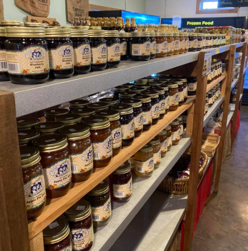 Shelves filled with jars of various jams and preserves, neatly arranged in a store.