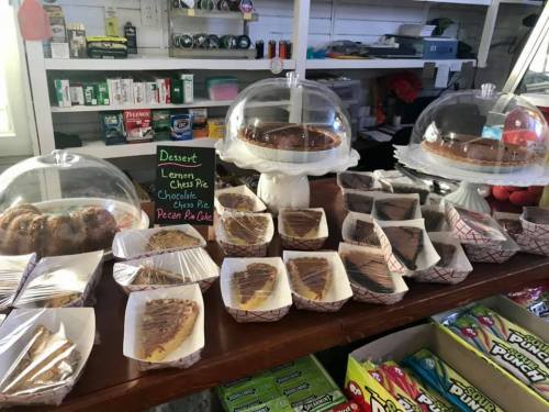 A display of various desserts, including pies and cookies, under glass domes on a wooden counter.