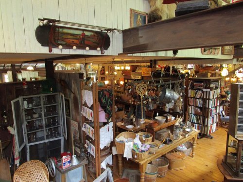 A cozy antique shop filled with various vintage items, furniture, and warm lighting, creating a nostalgic atmosphere.