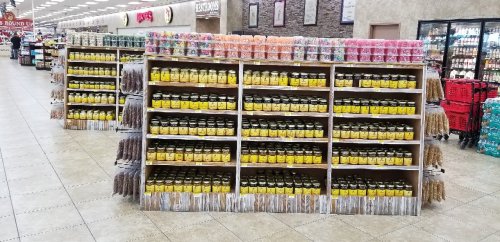 A store display featuring shelves filled with jars of yellow products and colorful candies on top.