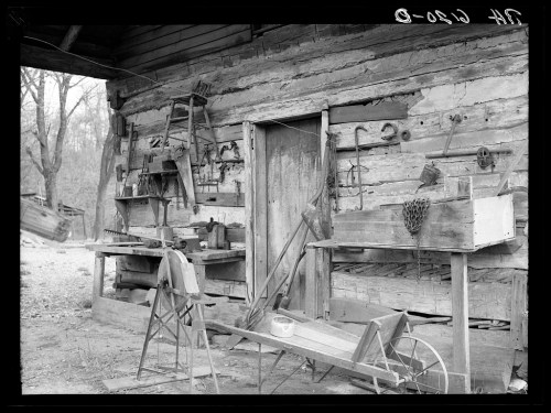 A rustic workshop with wooden walls, tools, and equipment scattered around, evoking a vintage, rural atmosphere.