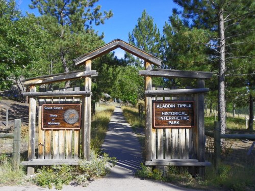 Entrance to Aladdin Tipple Historical Interpretive Park in Crook County, Wyoming, surrounded by trees and a clear blue sky.