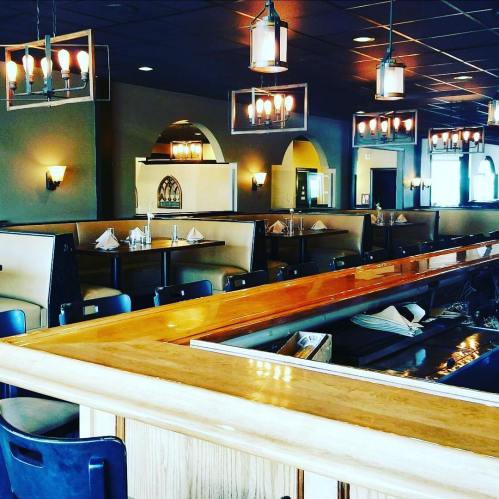 A spacious restaurant interior featuring wooden tables, booths, and stylish lighting fixtures.