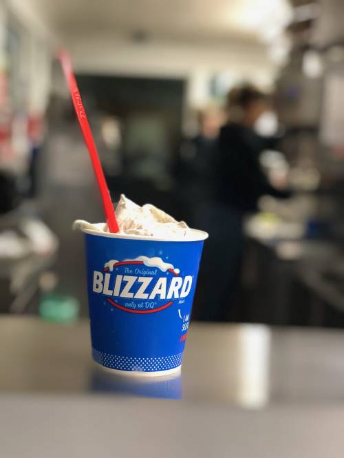 A cup of Blizzard dessert with a red spoon, set on a counter in a fast-food restaurant.