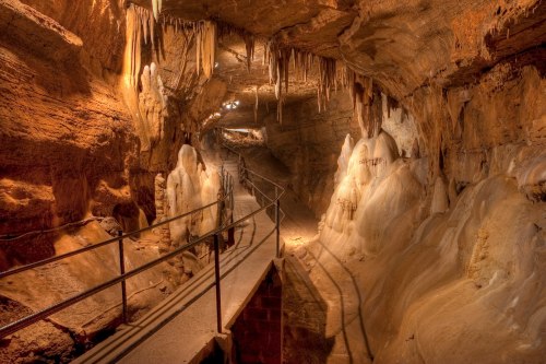 A dimly lit cave with stalactites and stalagmites, featuring a walkway for exploration.