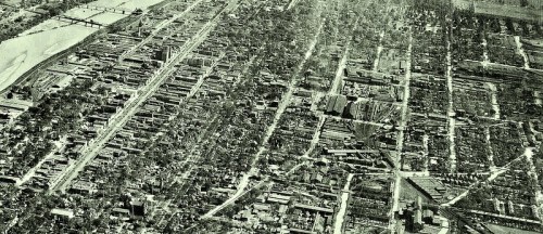 Aerial view of a cityscape showing extensive damage, with destroyed buildings and debris scattered across the landscape.